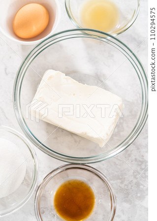 Measured ingredients in glass mixing bowls to make the cream cheese filling. 110294575