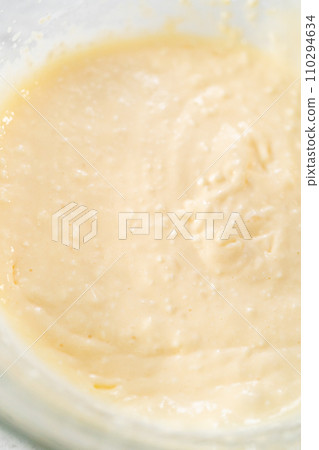 Mixing ingredients with a hand mixer in a large mixing bowl to make the cream cheese filling for carrot bundt cake. 110294634