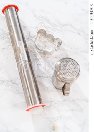 Rolling cookie dough and cutting out panda-shaped shortbread cookies. 110294708