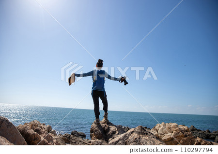 Woman photographer enjoy the view on sunrise seaside rocks Woman photographer enjoy the view on sunrise seaside rocks 110297794