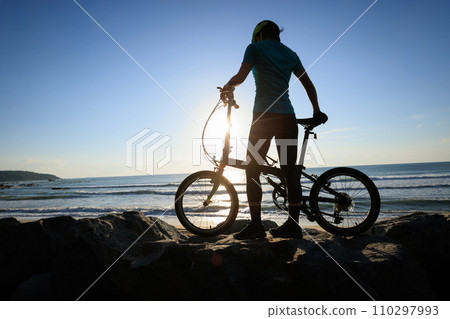 Riding folding bike on sunrise seaside road Riding folding bike on sunrise seaside road 110297993