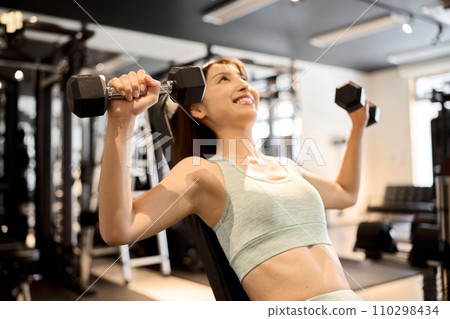 Woman training her chest with dumbbell presses 110298434