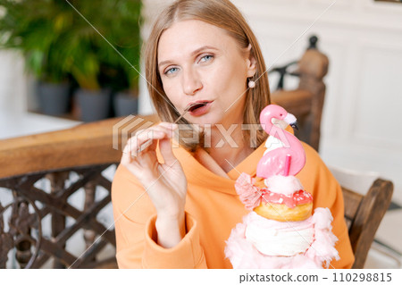 Happy woman eating sweet dessert in form pink flamingo in restaurant, woman 110298815