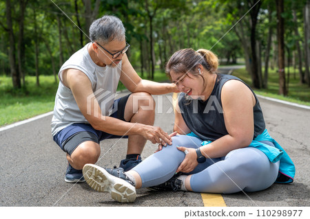 Young overweight woman checking the result of her morning run on her smart watch while standing at running track of a local park 110298977