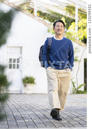 A man in his 50s walking with a backpack 110299381