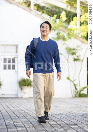 A man in his mid-50s walking with a backpack 110299426