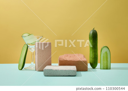 Front view of stone platforms, cucumbers and a cocktail displayed on a minimalist pastel background. Ideal space for product display. Natural ingredients good for the skin. Front view of stone platforms, cucumbers and a cocktail displayed on a minimalist pastel background. Ideal space for product display. Natural ingredients good for the skin. 110300544