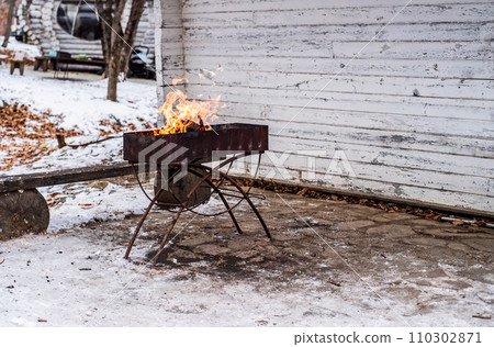 burning wood with fire in a barbecue grill in winter without people, copy space 110302871