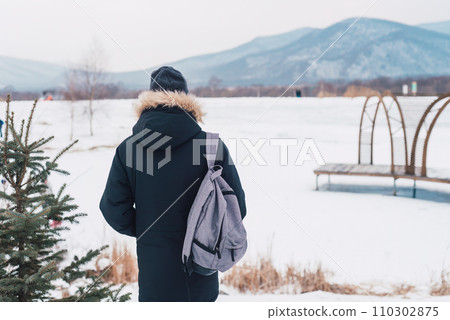 Young man solo traveler standing alone with backpack on winter background. Young man solo traveler standing alone with backpack on winter background. 110302875