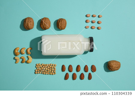 Empty label milk bottle surrounded by some handfuls of different types of nut. Maintain a healthy diet with soy products to improve your health. mockup design 110304339