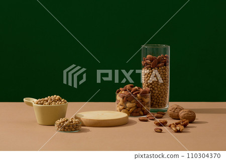 Various types of nuts are displayed over the dark background with a podium with vacant space. Minimal podium display for healthy product presentation 110304370