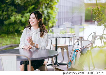 Business woman drinking smoothie, shake, and juice on the terrace of a cafe Business woman drinking smoothie, shake, and juice on the terrace of a cafe 110304714