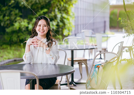 Business woman drinking smoothie, shake, and juice on the terrace of a cafe Business woman drinking smoothie, shake, and juice on the terrace of a cafe 110304715