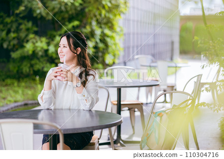 Business woman drinking smoothie, shake, and juice on the terrace of a cafe Business woman drinking smoothie, shake, and juice on the terrace of a cafe 110304716