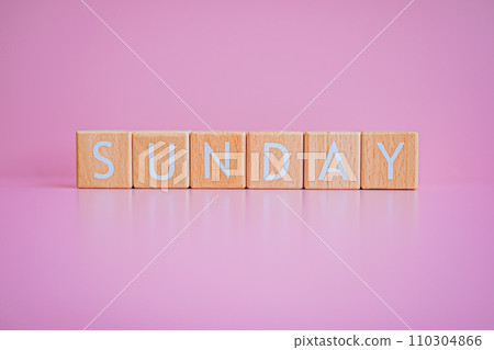 Wooden blocks form the text "SUNDAY" against a pink background. 110304866