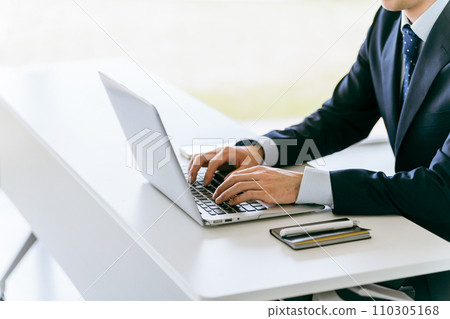 一個穿著西裝的男人的手在筆記型電腦上打字 110305168