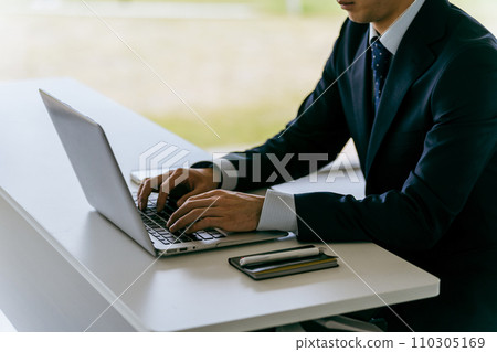 一個穿著西裝的男人的手在筆記型電腦上打字 110305169