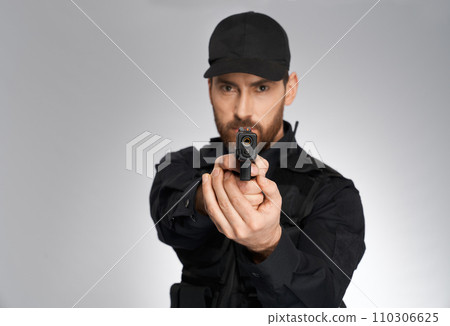 Serious bearded cop aiming, by pointing handgun to camera indoors. Portrait of young policeman shooting with gun, looking straight,isolated on gray background. Concept of danger, work, weapon. Serious bearded cop aiming, by pointing handgun to camera indoors. Portrait of young policeman shooting with gun, looking straight,isolated on gray background. Concept of danger, work, weapon. 110306625