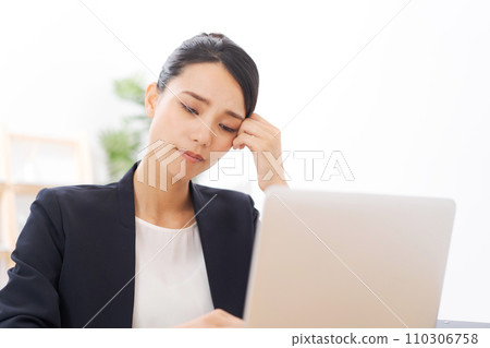 A woman in her 20s in a suit holding her head A woman in her 20s in a suit holding her head 110306758