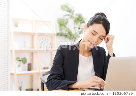 A woman in her 20s in a suit holding her head 110306759