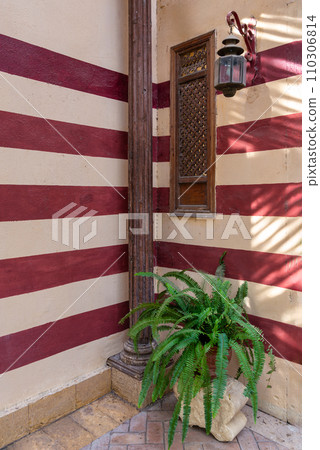 Mamluk architecture: rustic charm, weathered wooden window with star pattern, against aged brick wall 110306814