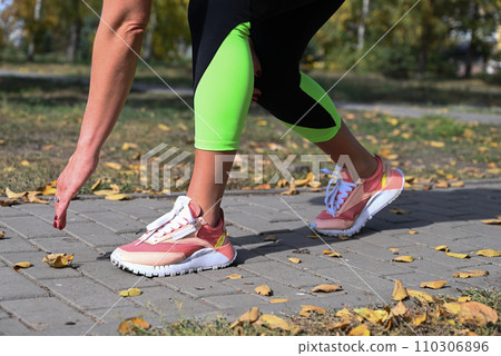 An athlete in comfortable sportswear. Outdoor fitness in the city. Healthy lifestyle. Coach exercises on the street. A confident woman does a workout. An athlete in comfortable sportswear. Outdoor fitness in the city. Healthy lifestyle. Coach exercises on the street. A confident woman does a workout. 110306896
