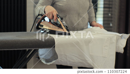 Woman using iron with steam mode for wrinkled clothes. Home Routine Housekeeping. 110307224
