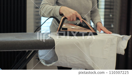 Woman using iron with steam mode for wrinkled clothes. Home Routine Housekeeping. 110307225