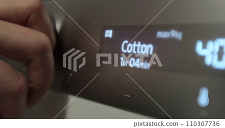 Woman rotating start button. Hand rotating the front panel button, switches different programs the washing machine. Clothes cleaning, laundry service. 110307736
