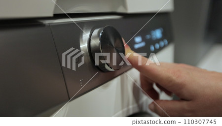 Woman press the switch to make the washing machine work. Home appliances. Laundry setting washing machine. Woman press the switch to make the washing machine work. Home appliances. Laundry setting washing machine. 110307745