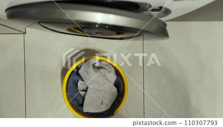 Close-up, top view. Woman loads the washer with dirty laundry. Washing clothing in domestic washing machine. Close-up, top view. Woman loads the washer with dirty laundry. Washing clothing in domestic washing machine. 110307793