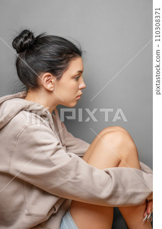 Pensive thoughtful young girl wearing sweatshirt with hood Pensive thoughtful young girl wearing sweatshirt with hood 110308371