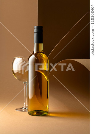 Bottle and glass of white wine on a beige background. 110308404