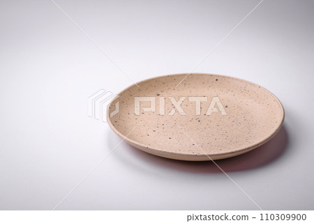 Empty round ceramic plate on a plain background, flatley with copy space 110309900