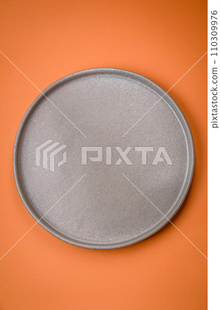 Empty round ceramic plate on a plain background, flatley with copy space 110309976