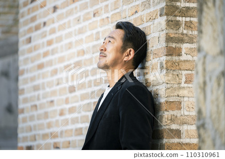 一名 50 多歲男子靠在磚牆上的肖像 110310961