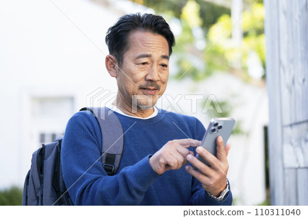一名 50 多歲的男子正在操作智慧型手機 110311040