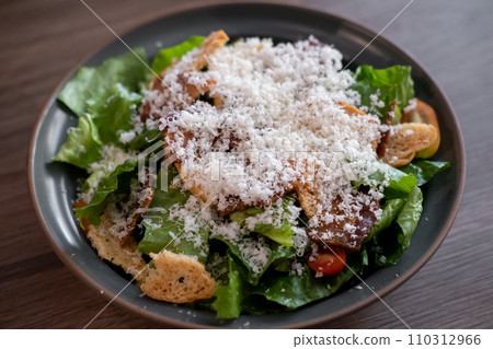 Caesar salad served on plate. Green salad with lettuce and croutons and parmesan cheese on top 110312966