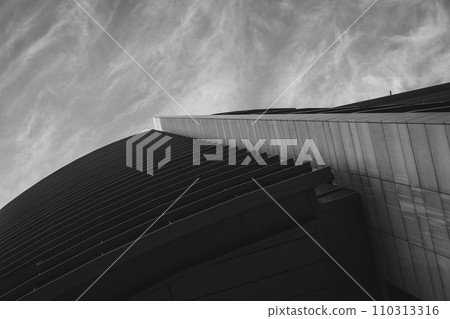 Abstract upward view of a modern buildings sharp lines against a dramatic sky, emphasizing urban architectural design Abstract upward view of a modern buildings sharp lines against a dramatic sky, emphasizing urban architectural design 110313316