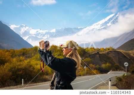 Girl taking pictures of mountain landscape Girl taking pictures of mountain landscape 110314343