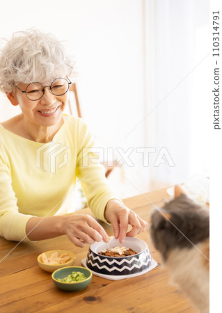 Senior woman preparing cat food (cat/owner) Senior woman preparing cat food (cat/owner) 110314791