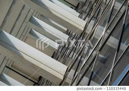 Diagonal view of a modern high-rise with intersecting lines and reflective windows, showcasing contemporary urban architecture. 110315448