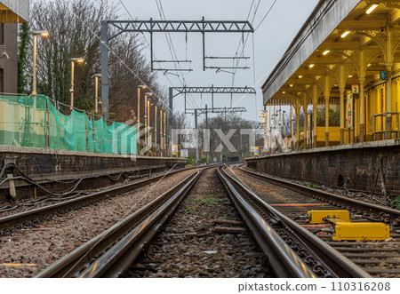 Perspective view on empty railway tracks and electric infrastructure equipment, wires at Acton central rail station. 110316208