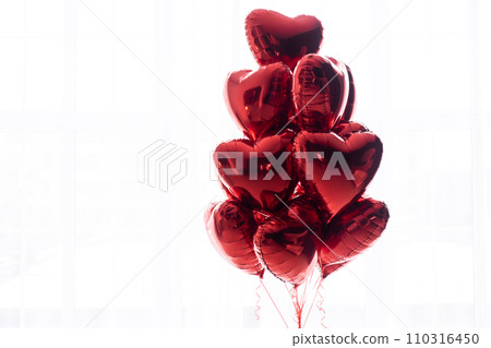 A floating bouquet of red, heart-shaped balloons on a white background. A floating bouquet of red, heart-shaped balloons on a white background. 110316450