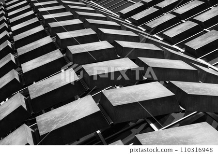 Monochromatic geometric pattern of building facade creating a dynamic play of light and shadow 110316948