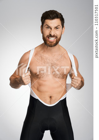 Aggressive caucasian wrestler in black and white singlet, while posing to camera. Portrait of sportsman grimacing, showing rage, isolated on white studio background. Concept of wrestling, sport. 110317501
