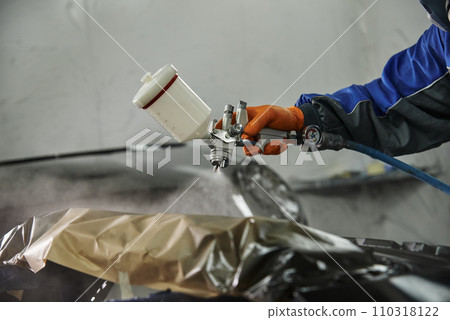 The photograph captures the scene of an automotive workshop, showcasing the process of painting various car parts. Different components of the vehicle car bonnet, bumpers, smaller details. The photograph captures the scene of an automotive workshop, showcasing the process of painting various car parts. Different components of the vehicle car bonnet, bumpers, smaller details. 110318122