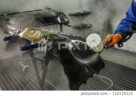 The photograph captures the scene of an automotive workshop, showcasing the process of painting various car parts. Different components of the vehicle car bonnet, bumpers, smaller details. The photograph captures the scene of an automotive workshop, showcasing the process of painting various car parts. Different components of the vehicle car bonnet, bumpers, smaller details. 110318123