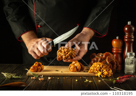 Chef preparing fresh velvet foot mushrooms in restaurant kitchen. The concept of preparing dietary wild mushrooms Flammulina velutipes for lunch Chef preparing fresh velvet foot mushrooms in restaurant kitchen. The concept of preparing dietary wild mushrooms Flammulina velutipes for lunch 110318195