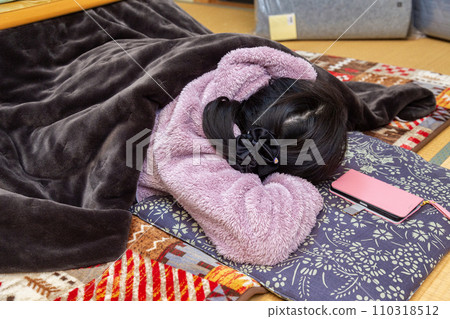 A woman taking a nap at a kotatsu in a Japanese-style room A woman taking a nap at a kotatsu in a Japanese-style room 110318512
